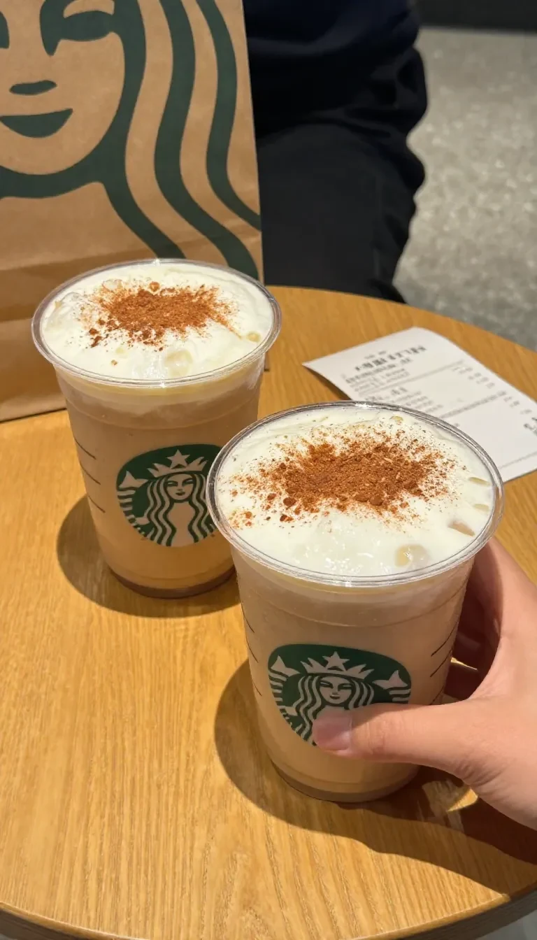 A glass of pumpkin chai tea topped with cold foam and a sprinkle of cinnamon on a wooden table.